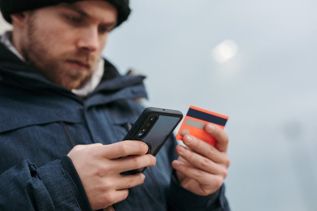 Man holding a credit card on one hand and a phone on the other